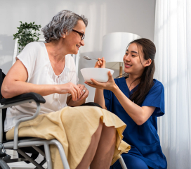 nurse woman is serving a food to senior woman