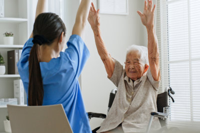 Nurse and senior woman are raising their hands