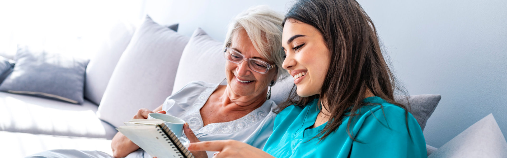 Young nurse spending time with happy elder patient in nursing home