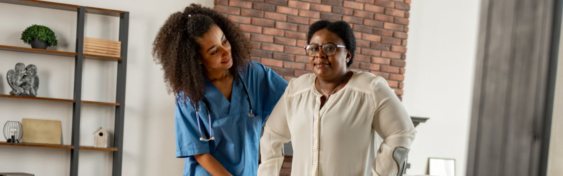 woman making first steps with crutches standing near private nurse