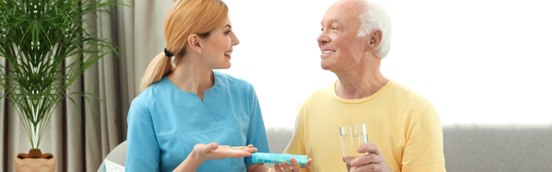 Nurse giving medication to elderly man indoors